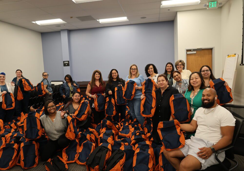 Staff posing with 600 assembled backpacks
