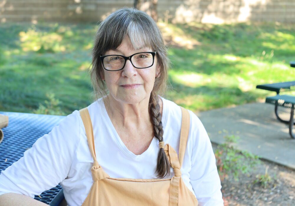 a photo of Patricia sitting at a blue bench