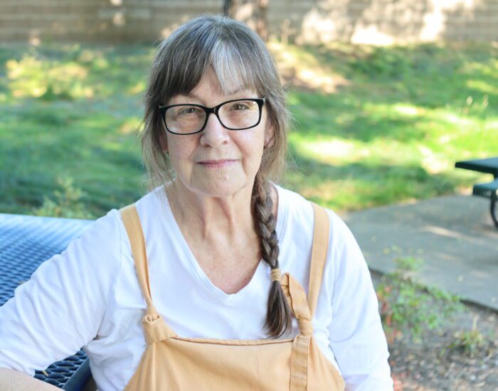 a photo of Patricia sitting at a blue bench