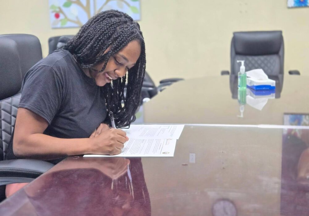 Mohagany sitting at a table writing on a paper