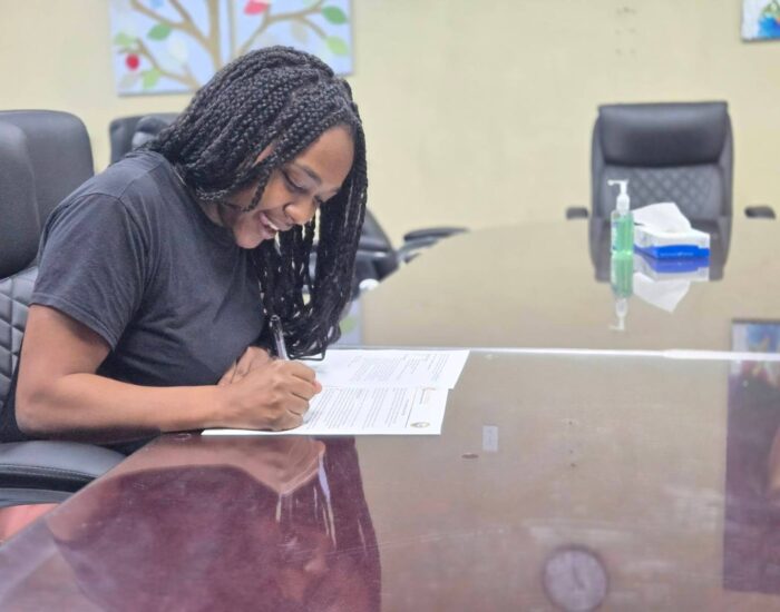 Mohagany sitting at a table writing on a paper